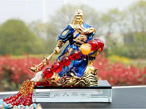 Close-up detail of golden Guan Yu car ornament featuring red crystal beads and base.