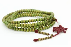 Primo piano di perline di legno verde con nodo Dharmachakra rosso per appendere in auto o bracciale.