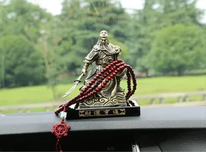Vista di dettaglio dell'ornamento per auto con statua in bronzo e perle rosse.