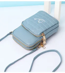 Detail view of the light blue mini phone bag featuring cute cat embroidery and double zippers.