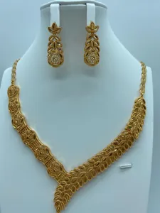Gedetailleerd overzicht van vintage vergulde sieradenset met bladketting en bijpassende oorbellen.