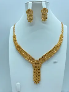 Gedetailleerd overzicht van de vergulde ketting en oorbellen set met verfijnde bladeren.