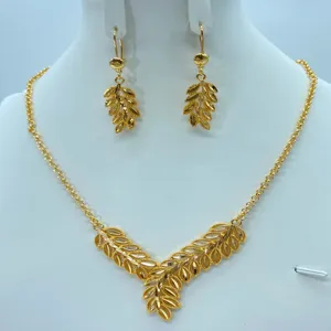 Gedetailleerde close-up van de elegante gouden bladhalsketting en oorbellen set.