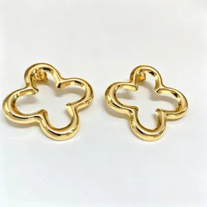 Gros plan de boucles d'oreilles clous fleurs creuses en or, texture métallique fine.