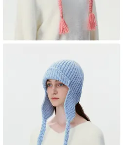 Knit aviator hat detail view, warm wool winter earflap cap with cute braided tassels.