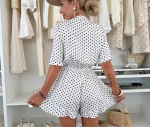 Detailed view of women white and black polka dot romper with ruffle hem in walk-in closet.