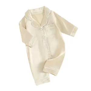 Vue détaillée de la combinaison pyjama bébé en satin champagne avec passepoil blanc.