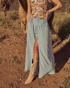 Detailed view of bohemian light blue denim maxi skirt with front buttons and high split.