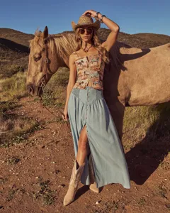 Detailed shot of bohemian style denim maxi skirt paired with western wear in outdoor setting.