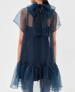 Back view of a dark blue sheer chiffon mini dress featuring a large bow and ruffled hem.