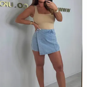 Asymmetrical denim mini skirt and beige tank top set, stylish casual outfit for women.