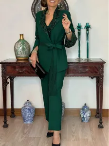Detailed view of emerald green sequin lapel blazer and pants set with stylish fringe belt.