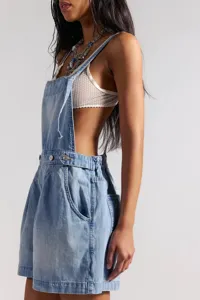 Close-up detail of light wash denim dungarees paired with layered necklaces and bralette.