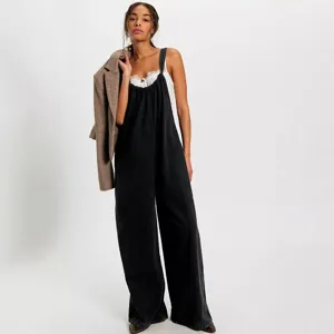 Close-up detail of the black loose casual denim jumpsuit, featuring a comfortable suspender design.