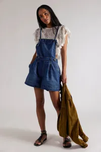 Detail view of women's denim overall shorts featuring stylish pleats and classic blue wash.