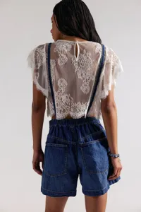 Detailed back view of casual women blue denim overalls shorts with white lace blouse top