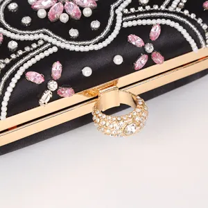 Close-up detail of black evening clutch bag, featuring exquisite beading, rhinestones and ring clasp.