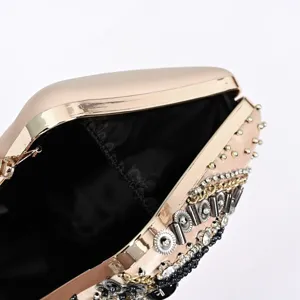 Close-up detail shot of luxury beaded evening clutch bag with metallic frame and rhinestones.