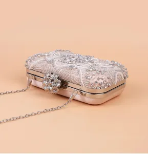 Detailed view of luxury rhinestone beaded evening clutch bag with metal flower clasp and chain.