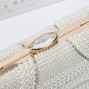 Close-up of elegant white pearl clutch bag with gold metallic frame and crystal clasp detail.