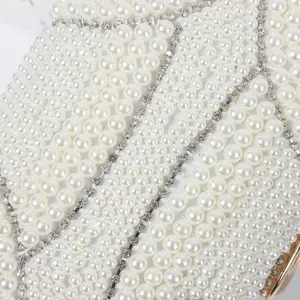Close-up detail of luxury pearl and rhinestone evening clutch bag surface texture craftsmanship.