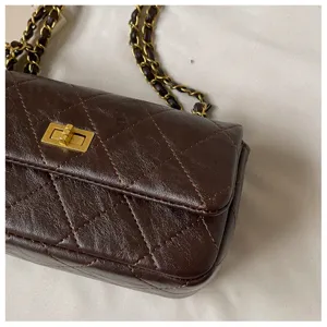 Dark brown quilted leather shoulder bag with gold tone turn lock and chain strap for daily style.