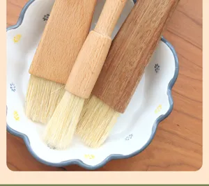 Wooden handle pastry and basting brush set in ceramic dish detail view for baking and cooking.