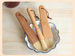 Detailed shot of wooden handle bristle brushes for baking and cleaning in a ceramic bowl.