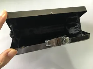 Close up of black metallic evening clutch bag with satin interior lining and secure metal clasp.