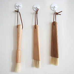 Wooden handle cleaning brush and BBQ pastry brush set hanging on wall for home kitchen baking use.