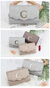 Detailed view of sparkly glitter evening clutch bag with metallic C logo for party dresses.