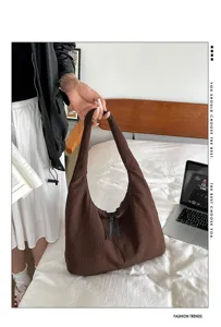 Detailed view of the brown slouchy hobo shoulder bag styled on a cozy bed setup.