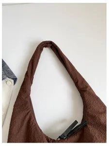 Brown slouchy shoulder bag detail showing soft textured fabric and zipper closure design.