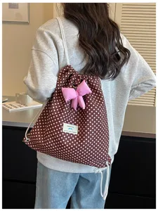 Gros plan détaillé du joli sac à dos à cordon à pois avec un charmant pendentif nœud rose.