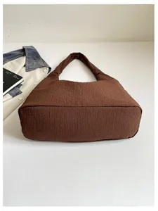 Brown textured shoulder bag detail showing crinkled fabric and wide strap design.