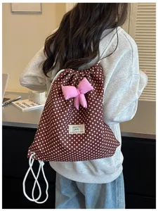 Vue détaillée d'un sac à dos cordon brun à pois avec nœud rose et étiquette en tissu.