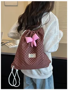 Vue détaillée du joli sac à dos à pois marron avec un adorable pendentif nœud rose.