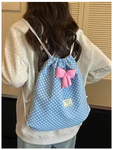 Vue détaillée d'un sac à dos cordon à pois bleus avec un joli nœud rose et étiquette.