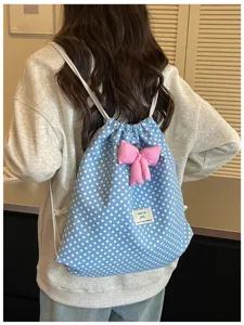 Vue détaillée d'un charmant sac à dos cordon à pois bleus et blancs avec un nœud rose.