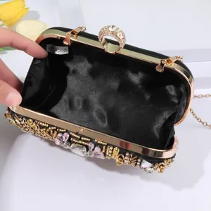 Black satin evening clutch bag with beaded rhinestone decor, gold frame and ring clasp.