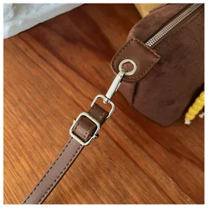 Detailaufnahme von braunem Wildleder-Umhängetasche-Gurt, silberne Metallbeschläge, Schnalle.