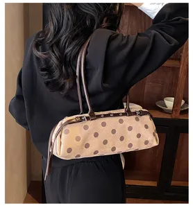 Detail shot of stylish brown polka dot baguette bag worn on shoulder for daily casual look.