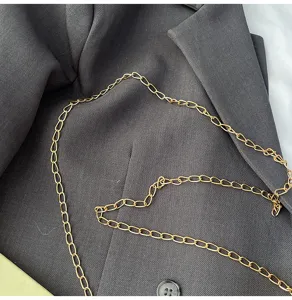 Detailed view of fashionable gold metal chain accessory on dark fabric for women's crossbody bag.