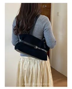 Details van zwarte suède schoudertas, retro tas met metalen gesp en riemdetail.