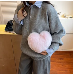 Close-up detail of the pink plush heart crossbody bag worn with casual grey knit sweater.