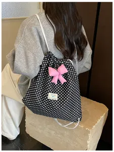 Vue détaillée du sac à dos à cordon avec motif à pois noir et blanc et nœud rose.