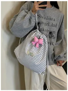 Gros plan du sac à dos à cordon à pois doux avec joli nœud rose et étiquette en tissu.