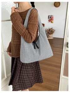 Detailed shot of a black and white checkered canvas shoulder bag with casual styling.