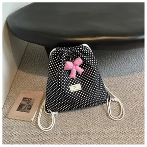 Gros plan détaillé du sac à dos à pois noirs avec joli nœud rose et étiquette en tissu.