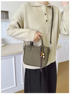 Schicke Umhängetasche mit Webstruktur und Holzperlen-Anhänger, elegante Retro-Beuteltasche Detail.